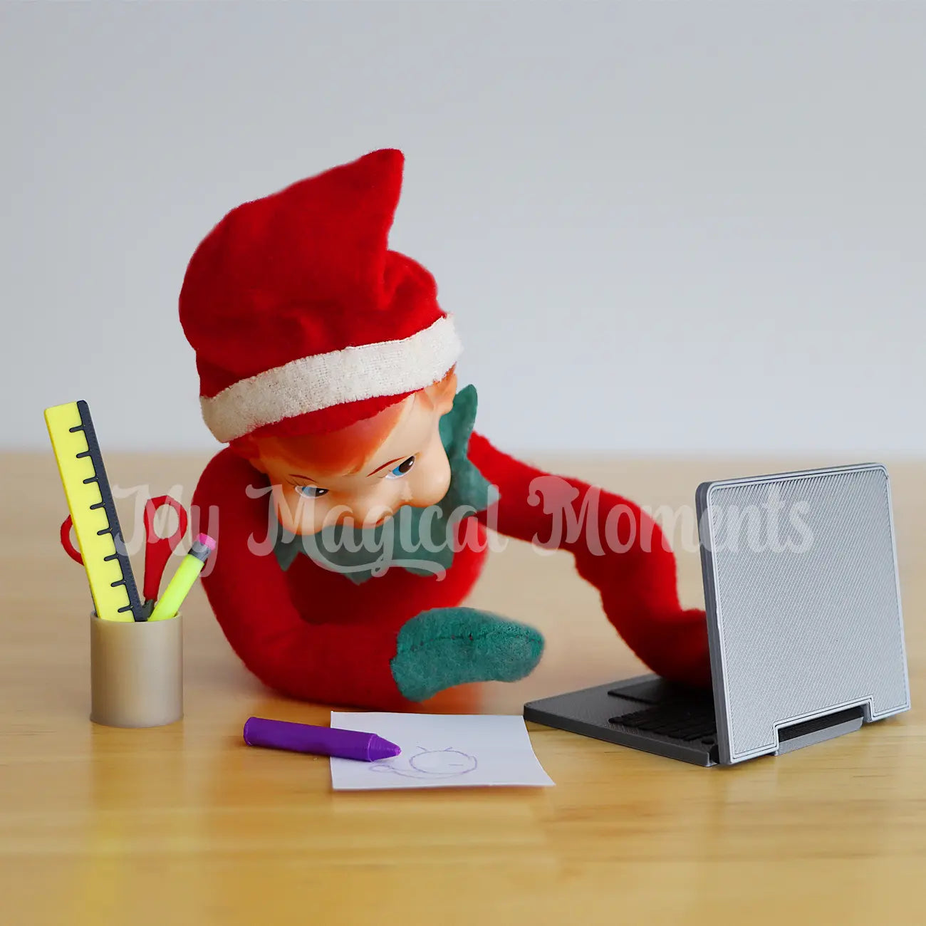 elf using a miniature laptop prop with mini crayons