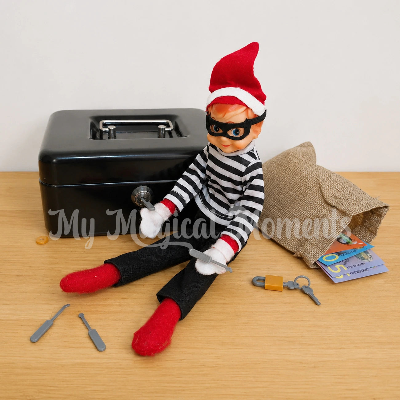 Elf picking a locked money box with mini locksmith tools, there is a padlock and keys and a sack with money in it. the elf is dressed as a burglar