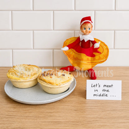 Elf wearing a meat pie costume with sauce, in a kitchen with meat pies on  a plate, with a sign saying Let's meat in the middle