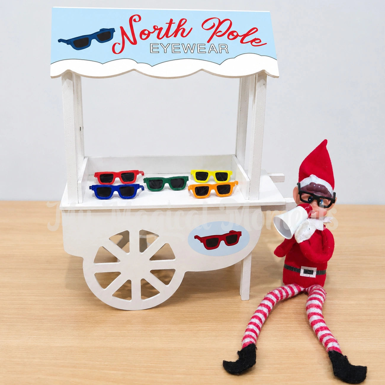 elf wearing glasses, holding a megaphone selling sunglasses from a little shop front