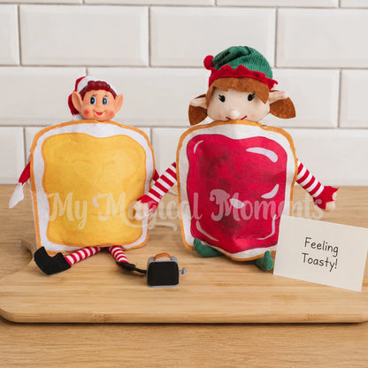 Elves wearing peanut butter and Jelly costumes, with a mini toaster that has toast in it. There is a sign that says Feeling Toasty