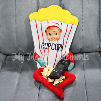 Elf dressed as popcorn eating popcorn with a tv remote