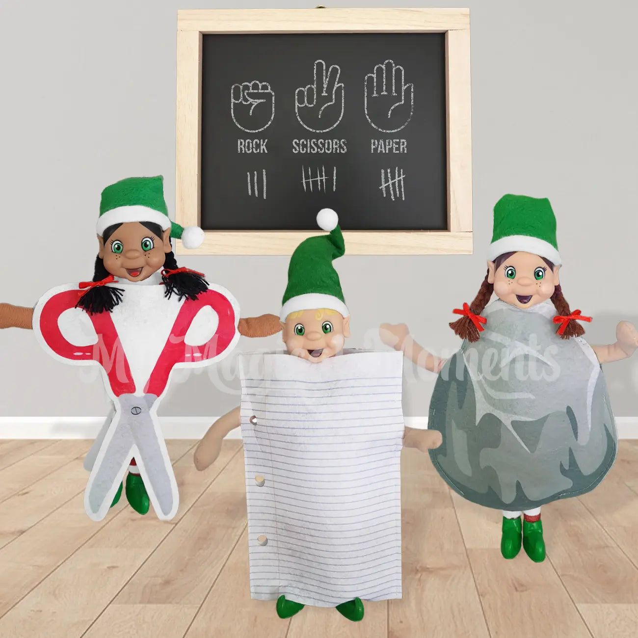 Elves in a room dressed up playing scissor, Paper, rock. There is a chalkboard behind them keeping score