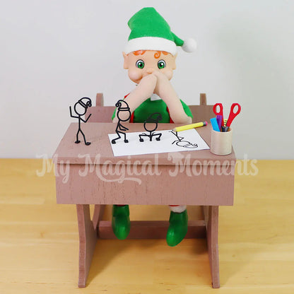 My Elf Friends Orange Hair Bendable Elf sitting in a mini wooden school desk  with 3d stick figures coming out of the page with mini pencils and scissors