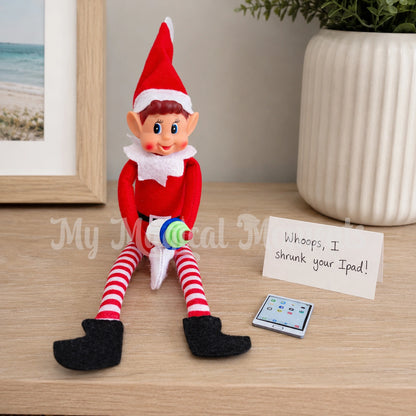 elf holding a shrink ray gun, shrinking an ipad. there is a sign that says Whoops, I shrunk your ipad