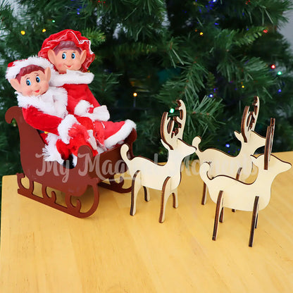 Elves dressed as Santa & Mrs Claus in a wooden sleigh with reindeers at a tree