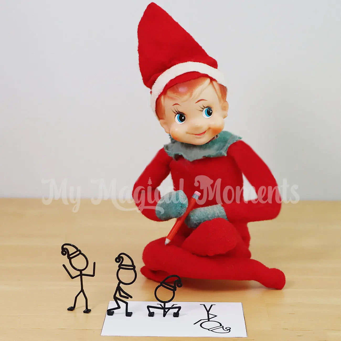 Elf Shelf holding a mini red pencil drawing stick figures coming to life in 3d form