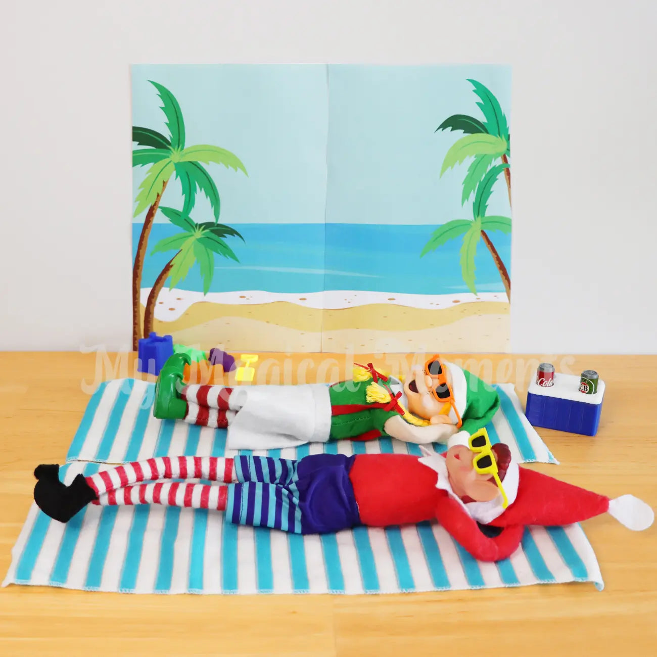 Elves sunbaking on mini towels, sunglasses, sand toys and a mini esky