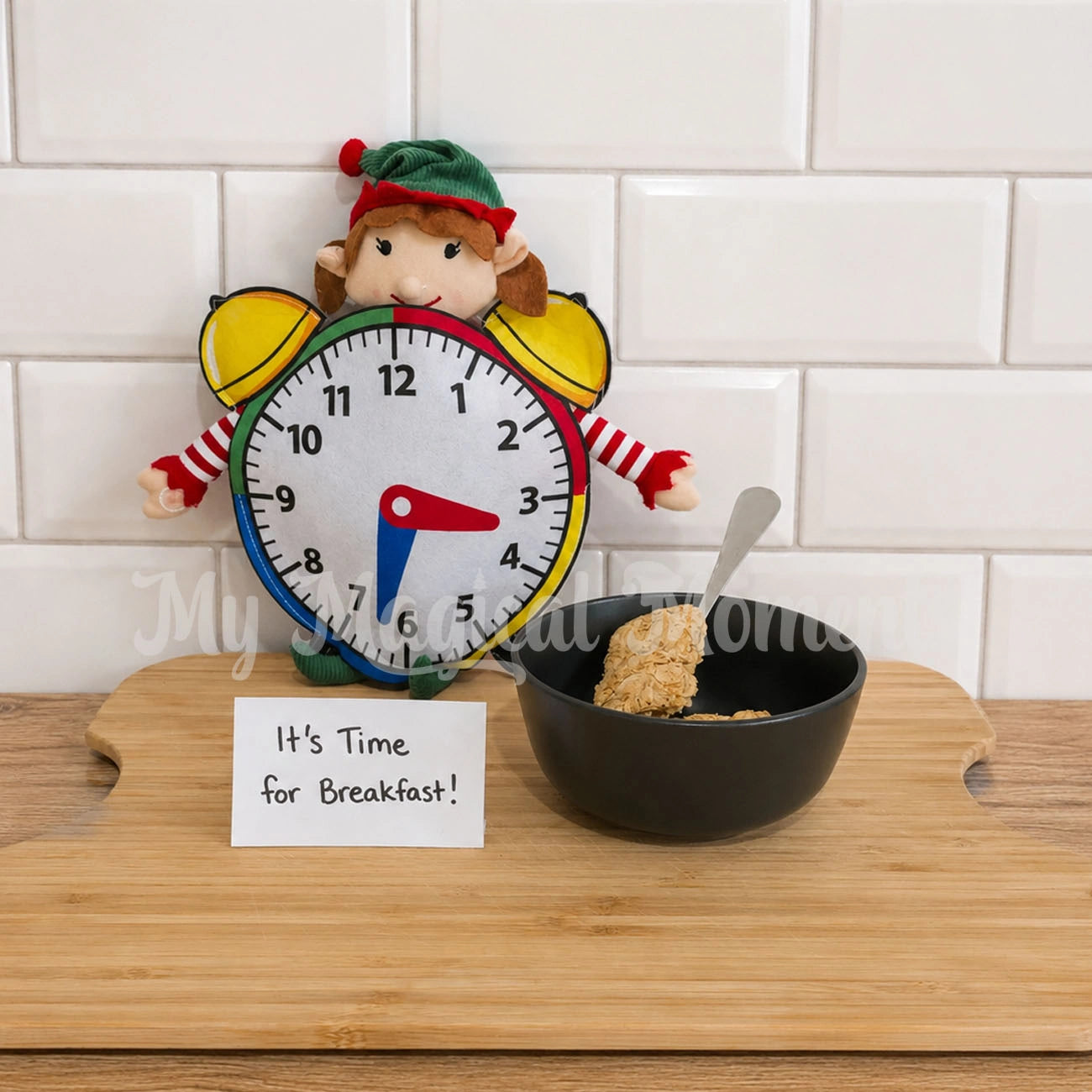 An Elf For Christmas wearing a clock costume sitting on a chopping board with a sign saying it's time for breakfast. There is a bowl of weatbix