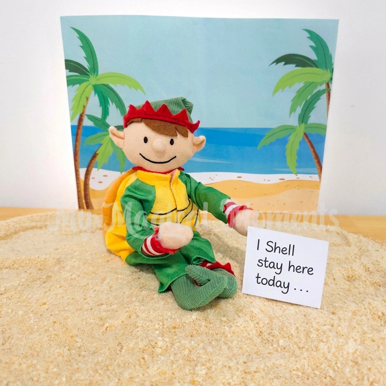 an elf for Christmas elf wearing a turtle costume, sitting on sand with a beach scene behind it