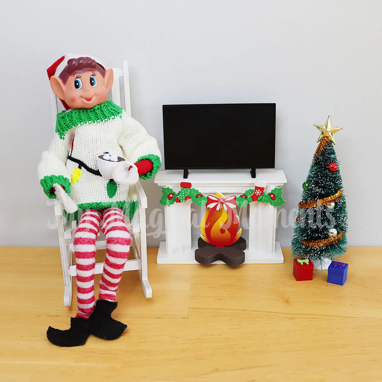 Ugly Sweater on an elf drinking hot cocoa with a fireplace and tree scene. Mini Elf tv