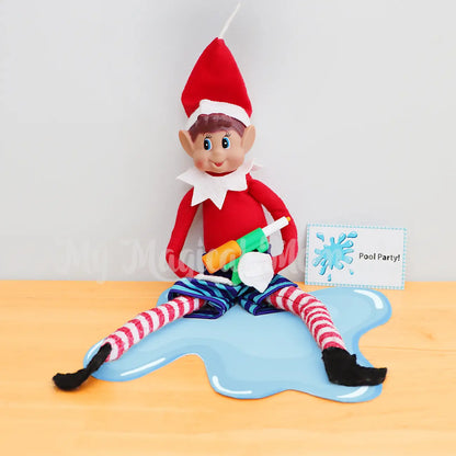 Elf holding a mini water gun in a puddle of water wearing boardshorts