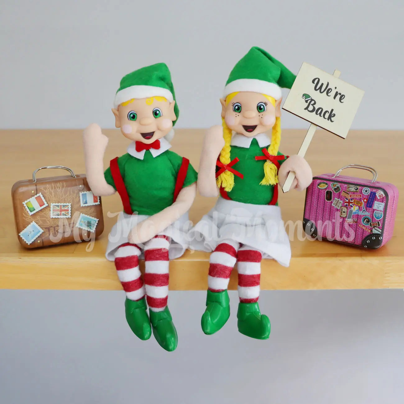 Blonde Hair Bendable Elves waving a we're back sign and suitcases