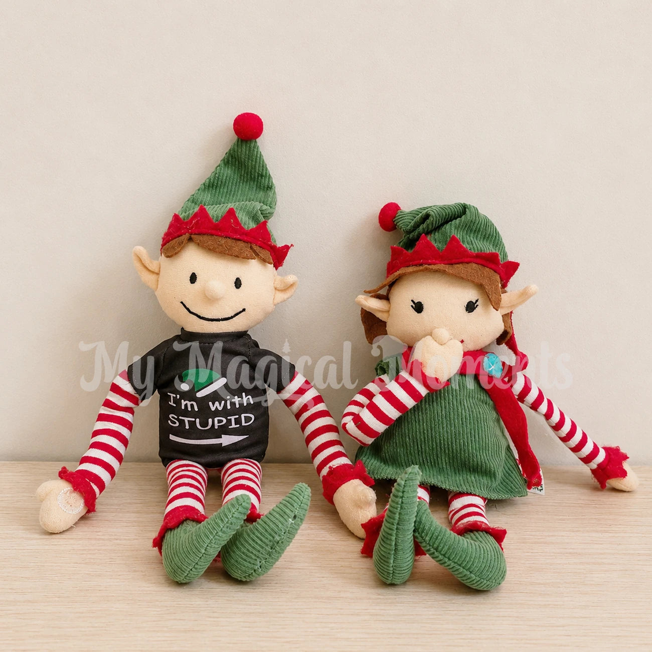 an elf for Christmas elf wearing an I'm with stupid shirt pointing to a girl elf