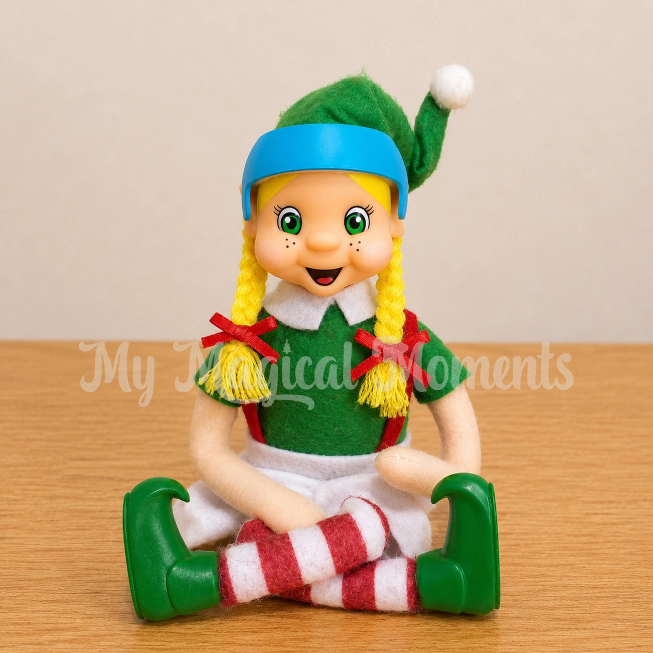 A blonde hair girl elf sitting wearing a blue miniature cranial therapy helmet