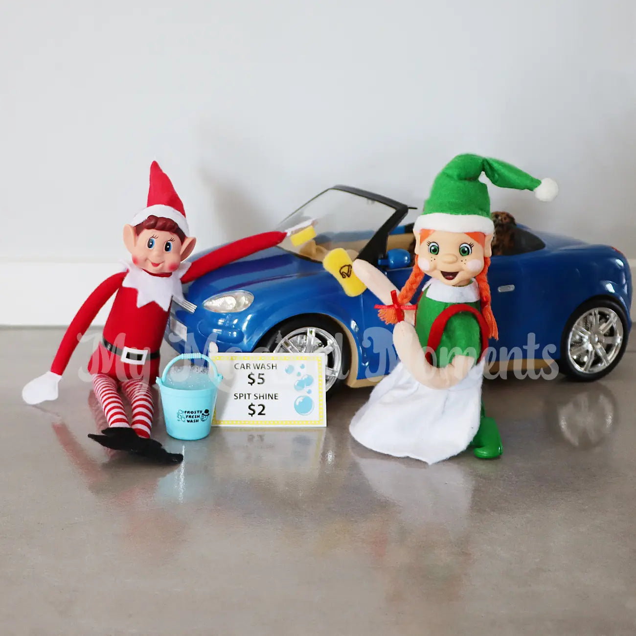 Elves washing a toy car with a mini bucket and sponge with frosty fresh on it