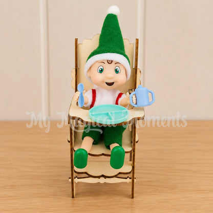 elf toddler sitting in a mini high chair with a tiny feeding set, plate spoon and sippy cup