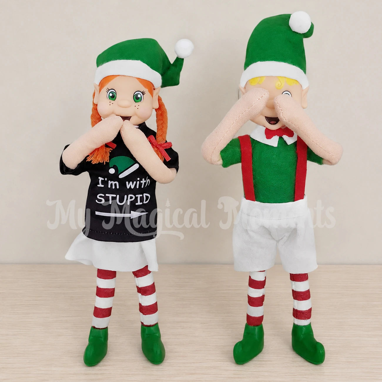 An elf with orange hair wearing an I'm with stupid shirt pointing to a blonde hair boy covering his eyes