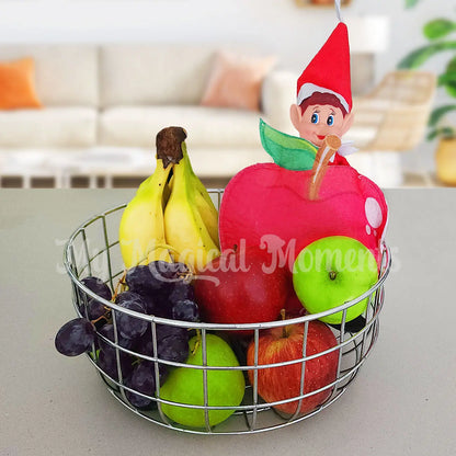 elf dressed as an apple in a fruit bowl