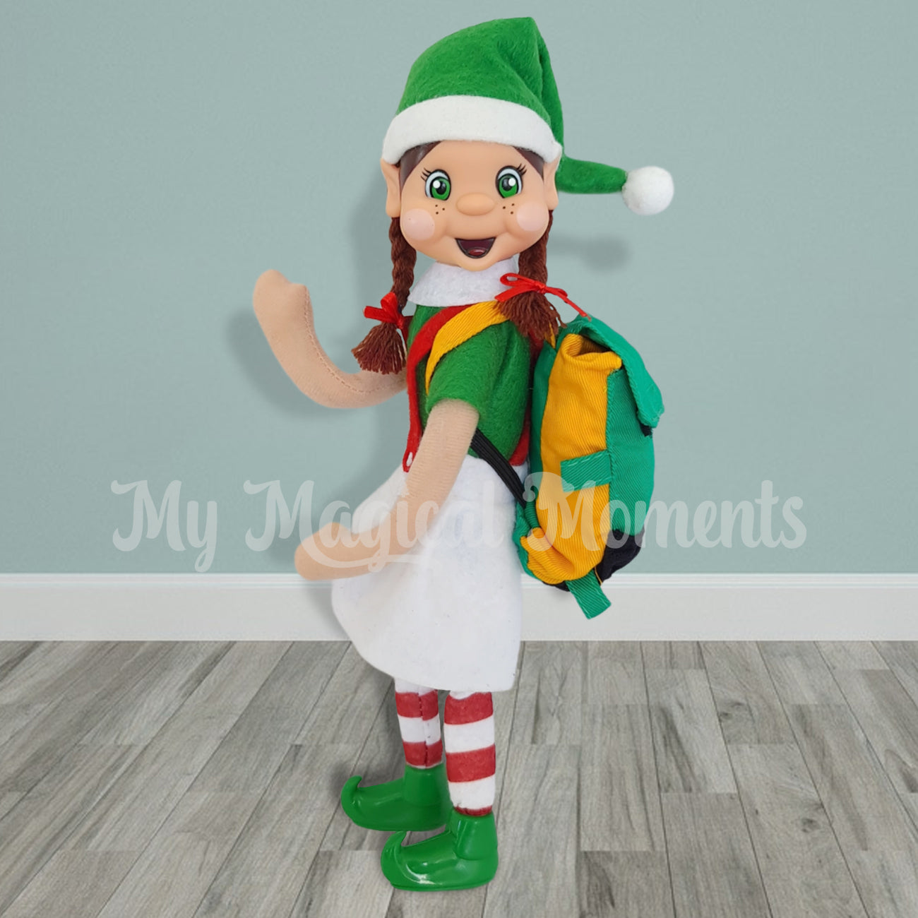 Brown hair girl elf friend standing and waving whilst wearing a green and yellow backpack