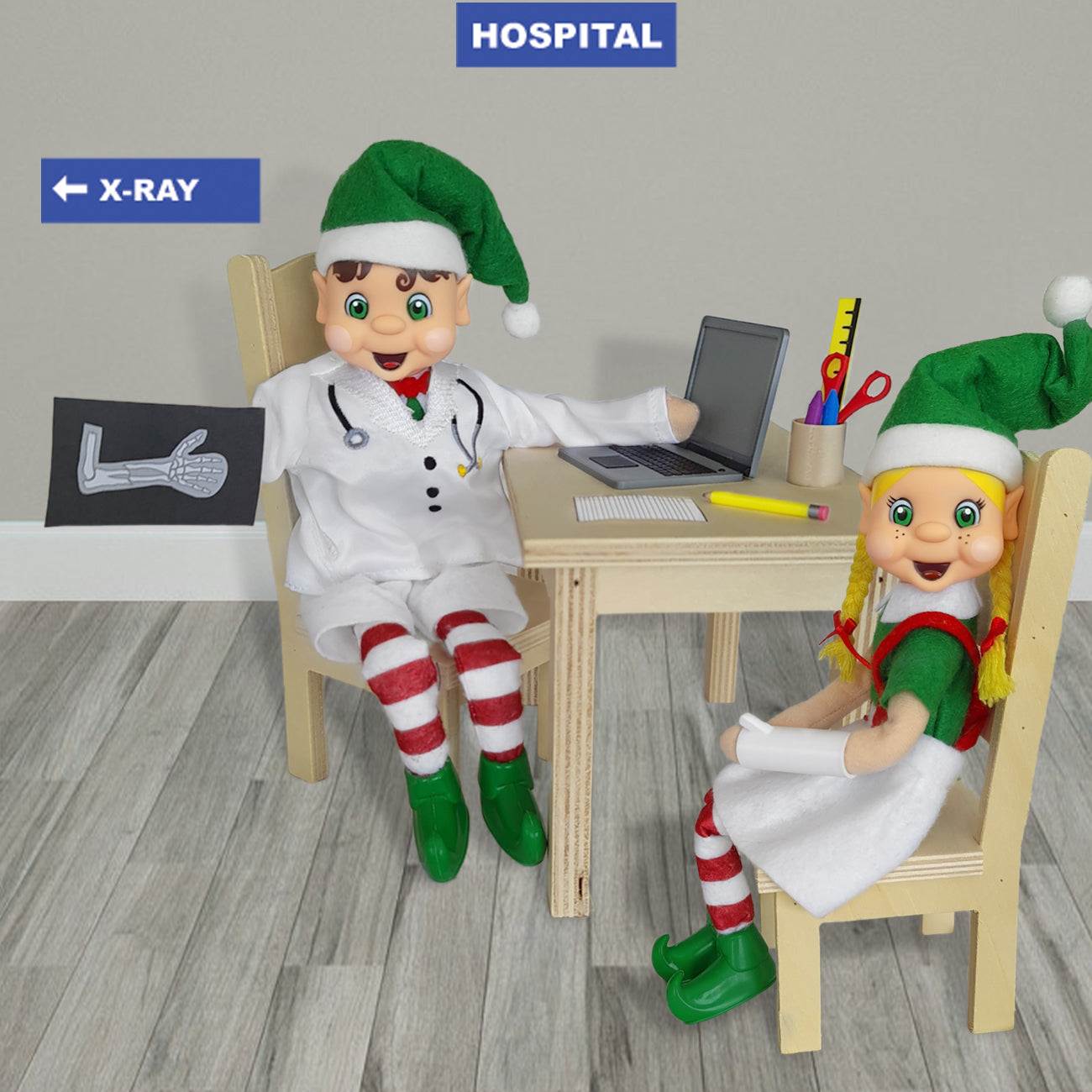 Broken arm scene, With a elf dressed as a doctor tending to a blonde hair elf with a broken arm. He has a elf sized laptop and pencils on his desk