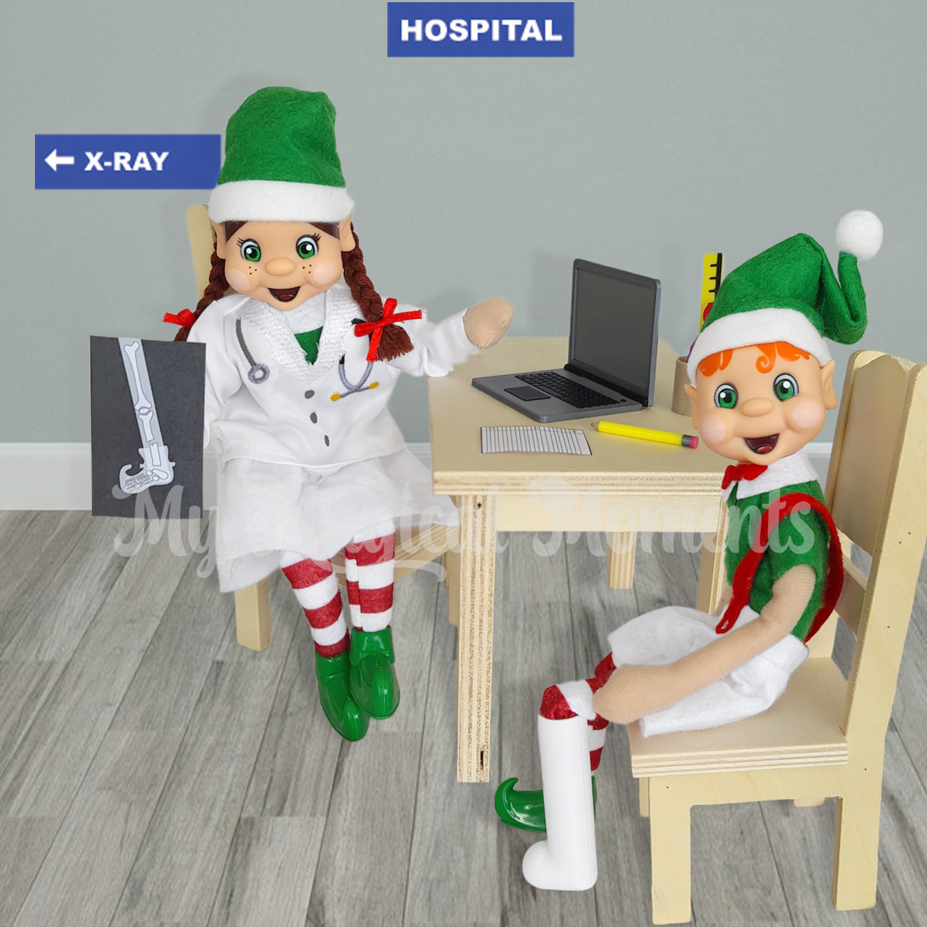 A brown hair girl elf dressed as a doctor holding a broken leg x-ray. There is a orange hair elf with a broken foot in a leg cast prop