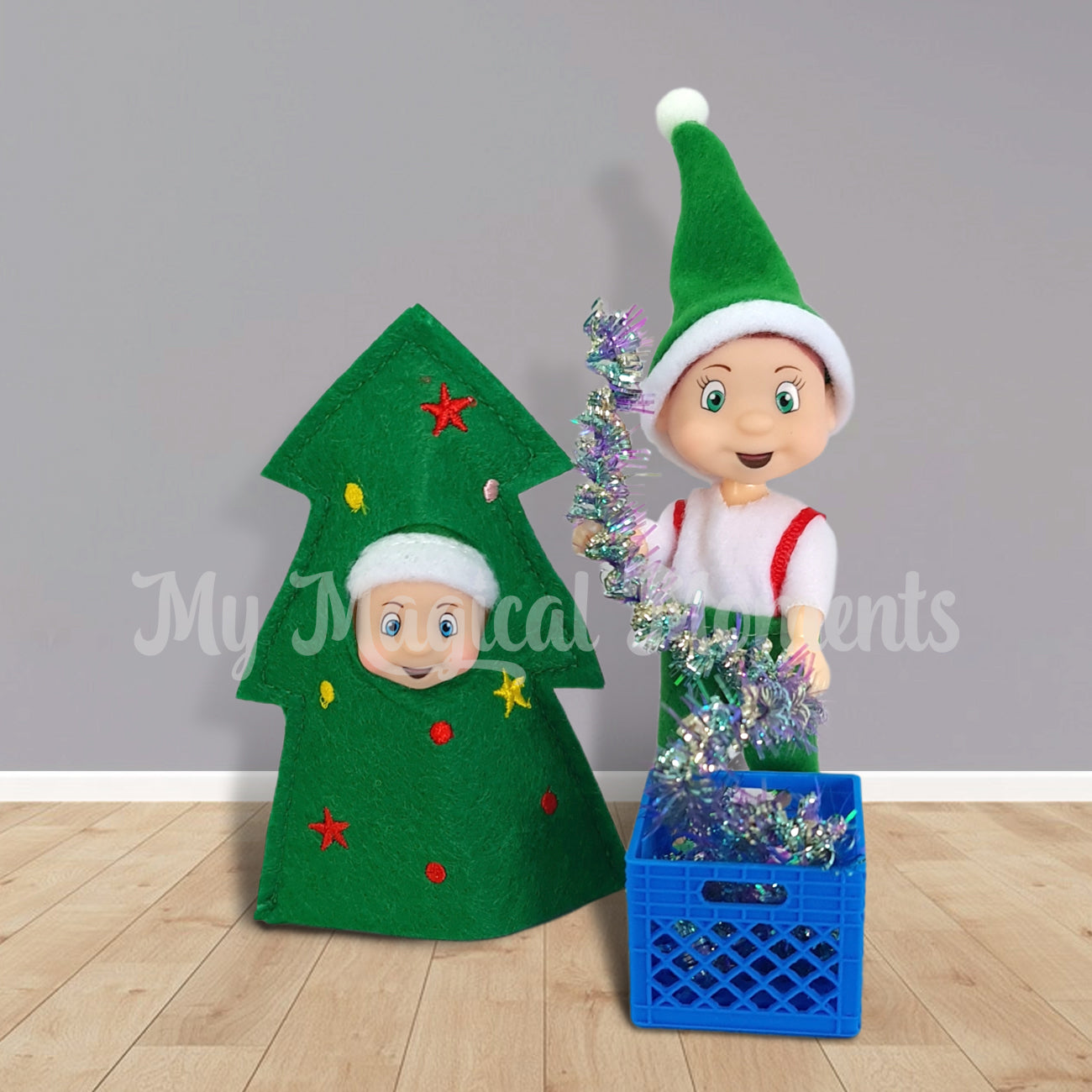 Toddler elf decorating a baby elf in a tree costume