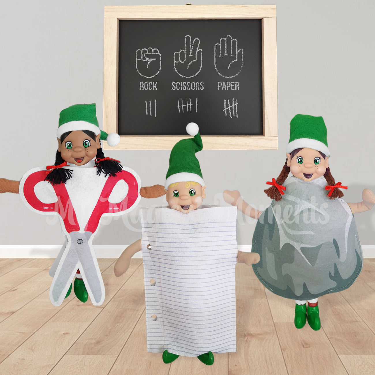 Elves in a room dressed up playing scissor, Paper, rock. There is a chalkboard behind them keeping score