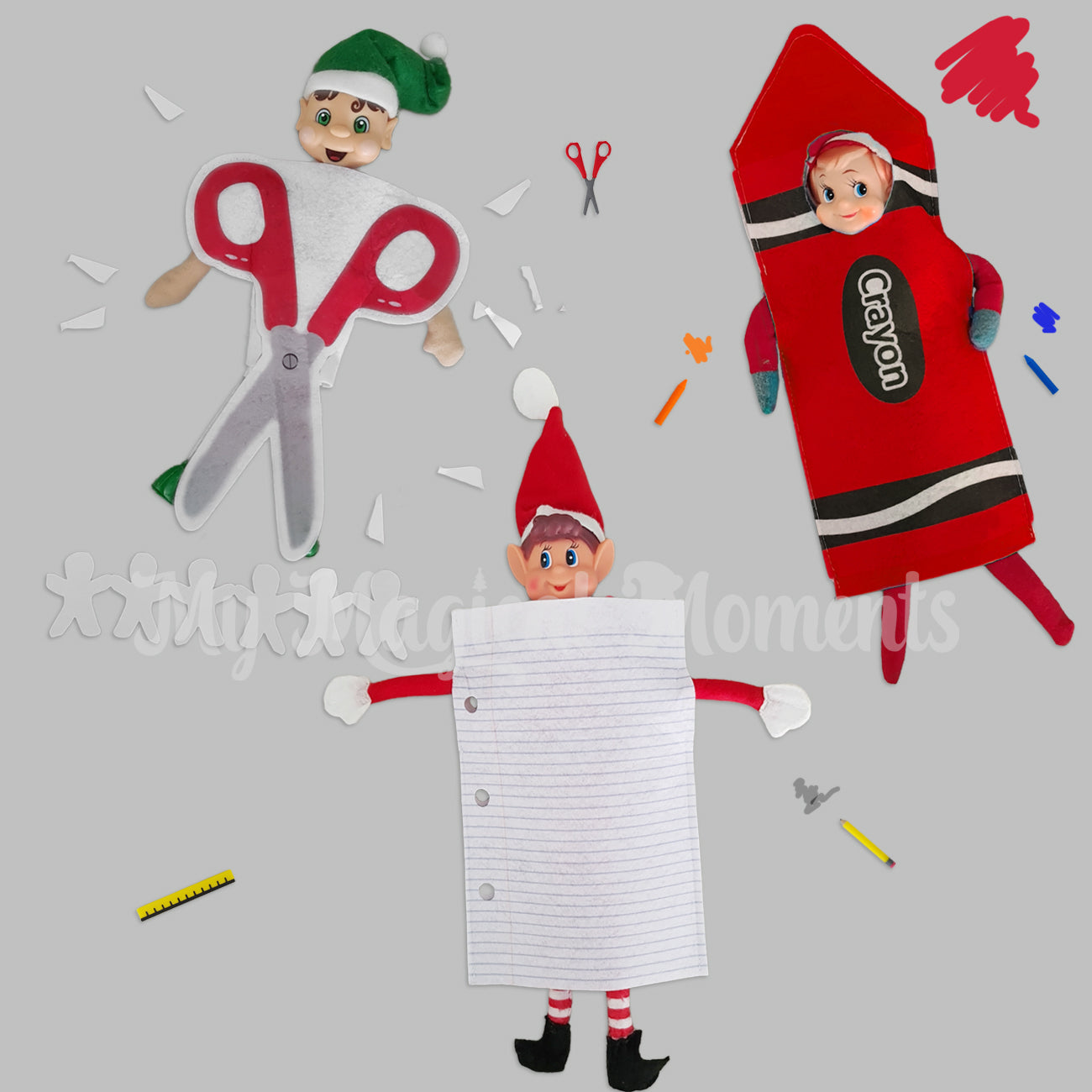3 elves dressed in costumes. One wearing a red pair of scissors, another elf dressed as paper and the last elf wearing a red crayon costume. There is elf sized scissors and crayons around them
