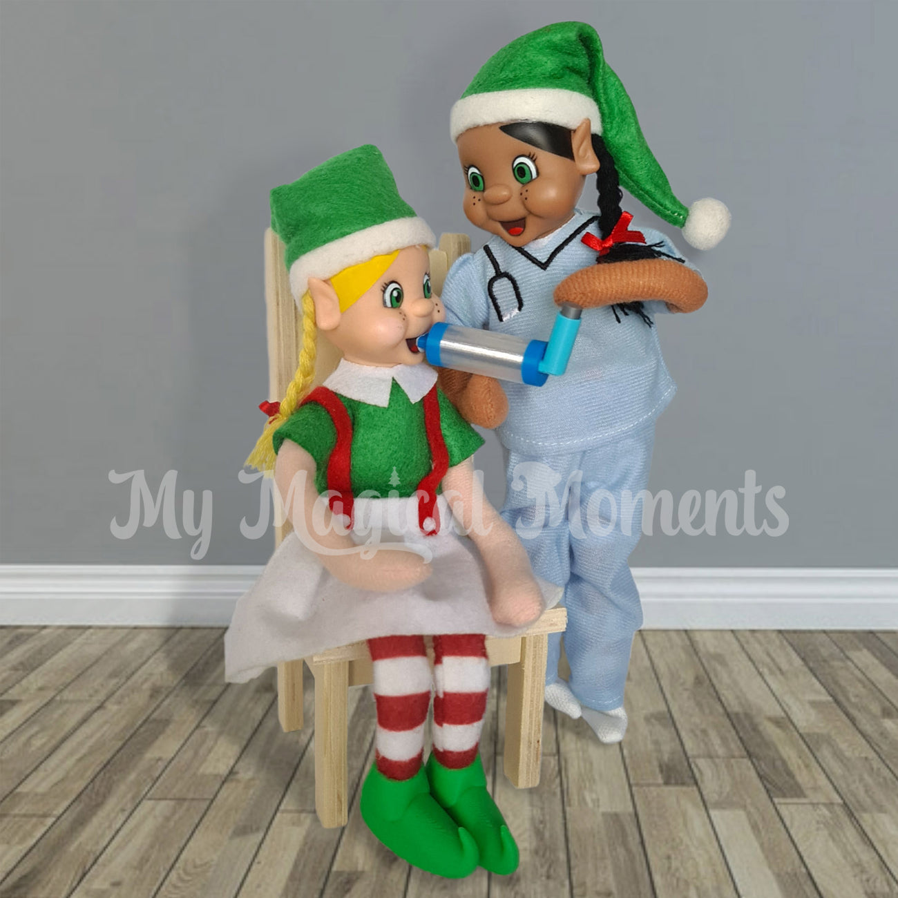 Asthma attack elf scene. A black haired elf dressed as a nurse giving an inhaler to blonde hair elf