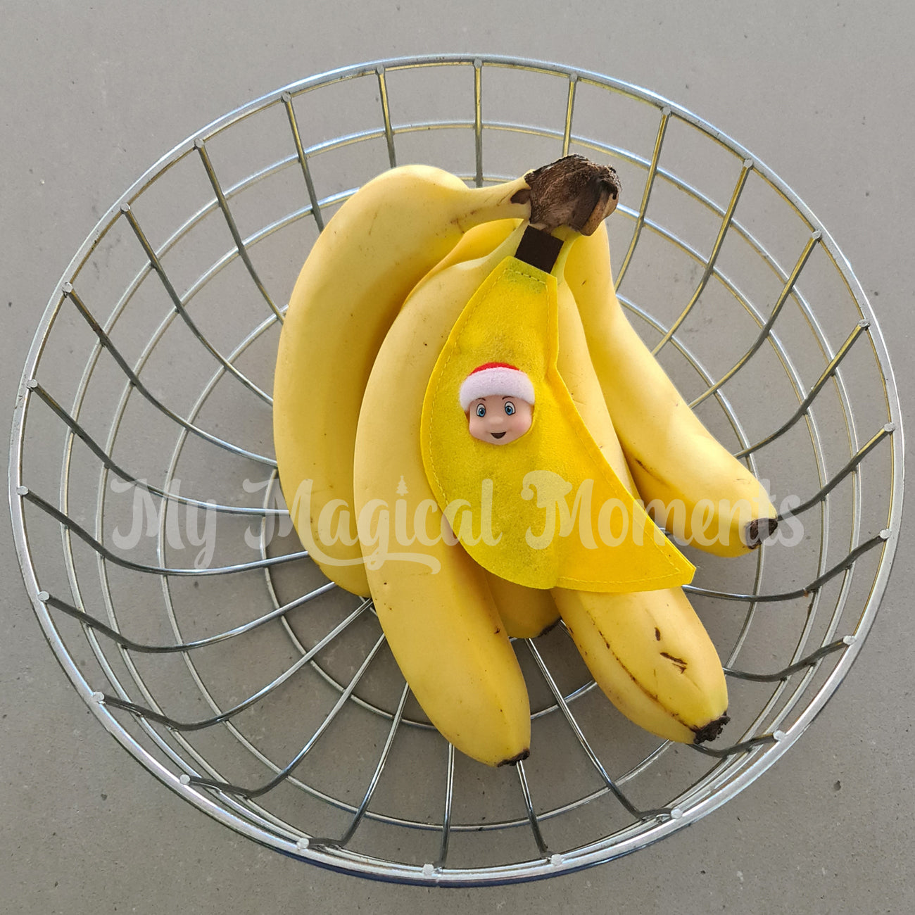 Elf baby dressed as a banana hiding in a fruit bowl