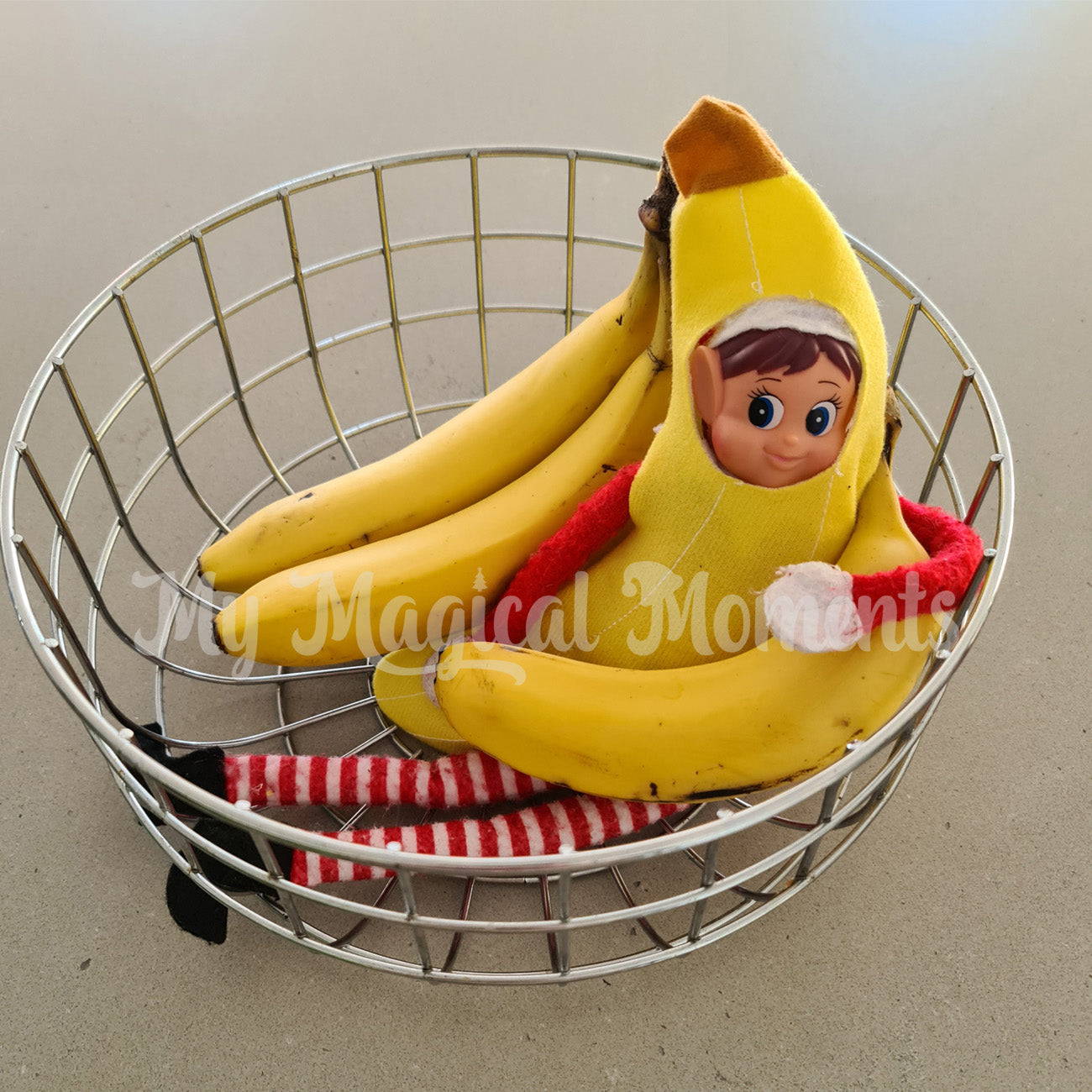 Elves behavin badly wearing a banana costume hiding in a bowl of fruit