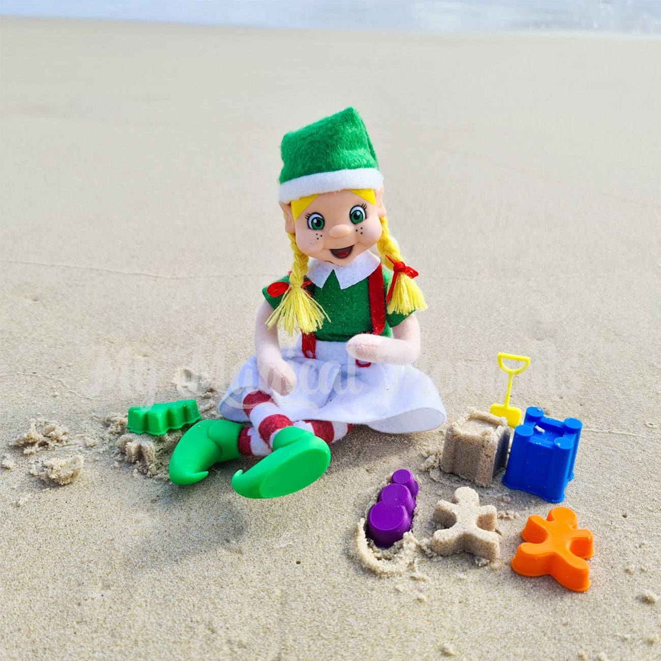 Elf playing at the beach making sand castles with miniature sand toys